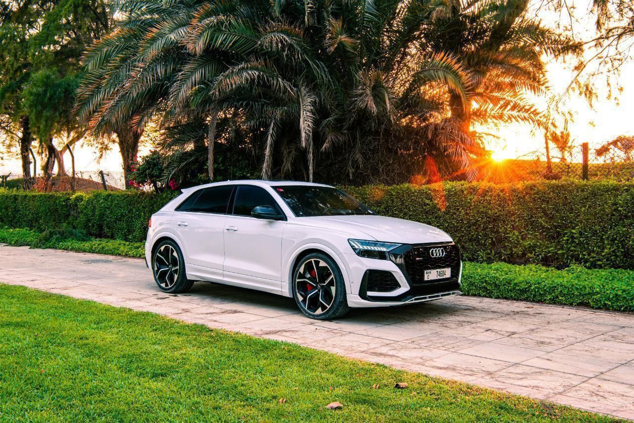 Audi RS Q8 blanche sous les palmiers à Dubaï au coucher du soleil